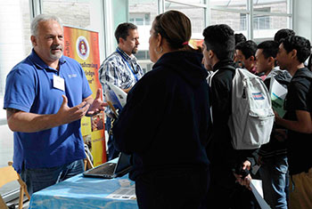 Two men talking to students at a career fair